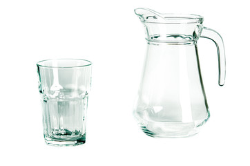 An empty glass glass and a carafe for water stand on a white background