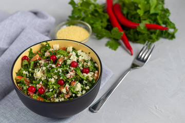 Tabule salad in a round plate on a light gray background under concrete.