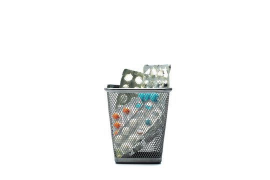 Metal trash bin with pills and blisters inside isolated on white.