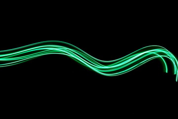 Long exposure photograph of neon green colour in an abstract swirl, parallel lines pattern against a black background. Light painting photography.