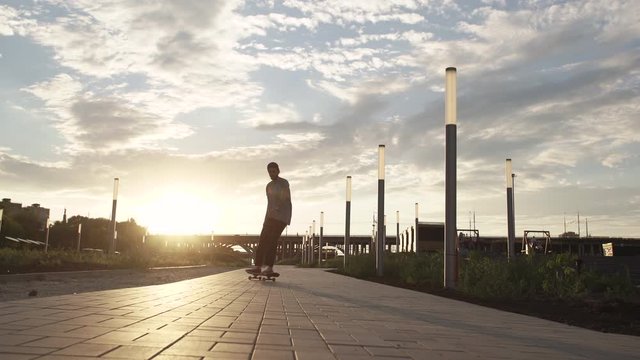 Young Pro Skateboarder Skateboarding In The Park In Sunset