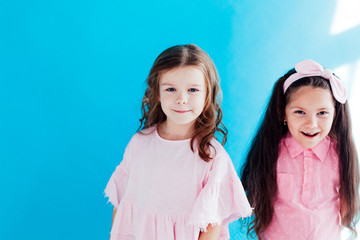 two little girls girlfriends together on blue background