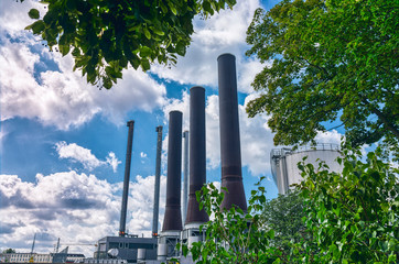Fototapeta premium three large chimneys of a power plant with a beautiful cloudy sky
