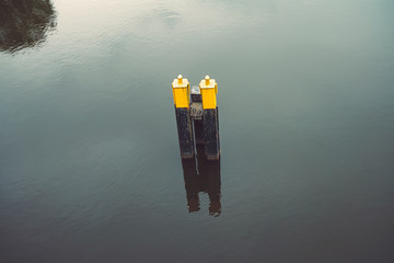 single yellow black mooring post in water
