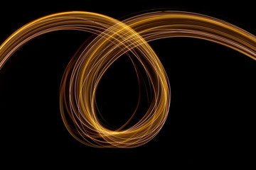 Long exposure photograph of neon colour in an abstract swirl, parallel lines pattern against a black background. Light painting photography.