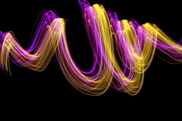 Long exposure photograph of neon colour in an abstract swirl, parallel lines pattern against a...