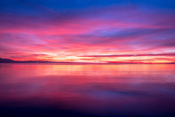 Fototapeta na wymiar dark violet clouds with orange sun light and pink light in wonderful twilight sky on lake Bodensee in Lindau