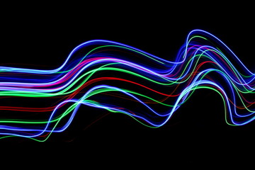 Long exposure photograph of neon colour in an abstract swirl, parallel lines pattern against a black background. Light painting photography.