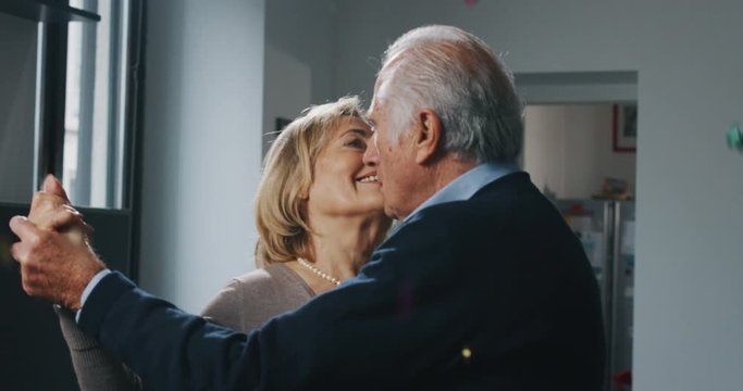 Close up of lovely senior couple is enjoying time together and dancing to celebrate their timeless love in living room at home.