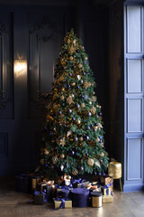 Beautiful and tall Christmas tree in the living room. Christmas presents near the tree.