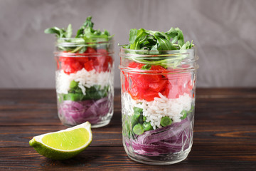 Healthy salad in glass jars on wooden table