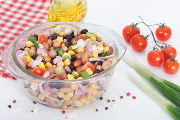 Vegetarian salad with red and black beans, chickpeas and corn in glass bowl on white background. Healthy vegan food.