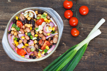 Vegetarian salad with red and black beans, chickpeas and corn in glass bowl. Healthy vegan food.
