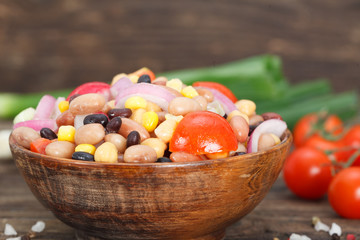 Vegetarian salad with red and black beans, chickpeas and corn in wooden bowl. Healthy vegan food with mixed vegetables.