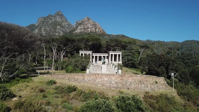 4K aerial summer sunny morning footage of beautiful green Devil's Peak slopes with white stone columns Cecil Rhodes Monument, Table Mountain National Park, Cape Town, Western Cape, South Africa