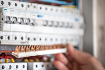 Man, an electrical technician working in a switchboard with fuses. Installation and connection of...