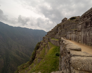 Machu Picchu Terraces and inca stone wall mountain range and clouds in the background