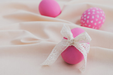 Pink easter eggs with ribbon on light pastel background. Minimal composition. Copy space, close up