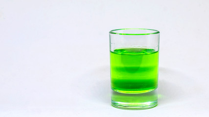 Small glass with a liquid, alcohol drink. Colored watery drink absinthe, curacao, cognac.