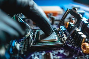 Fototapeta premium Engineer repairman holding hands CPU to insert into the socket of the motherboard. Technology hardware in the neon light