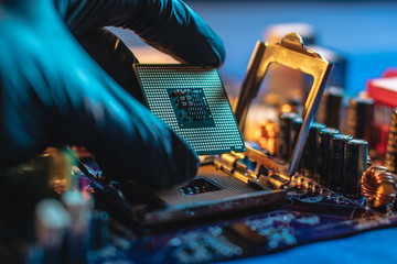 Engineer repairman holding hands CPU to insert into the socket of the motherboard. Technology hardware in the neon light - obrazy, fototapety, plakaty