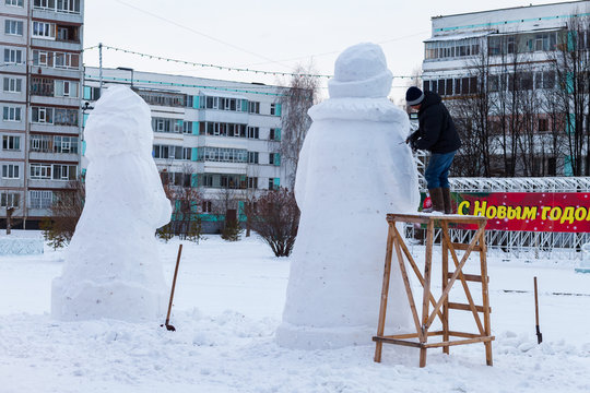A man builds a snowman Russian Santa Claus. Inscription on the background Happy new year.