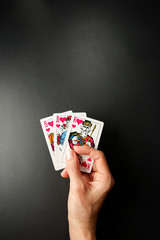 Cards in a hand on a black background. Three Card Poker. Rules and combinations of the game. Straight flush