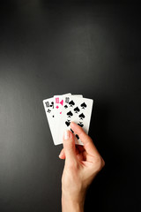 Cards in a hand on a black background. Three Card Poker. Rules and combinations of the game.  Three of a kind