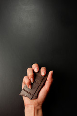 Dark chocolate in the hand. Empty blackboard