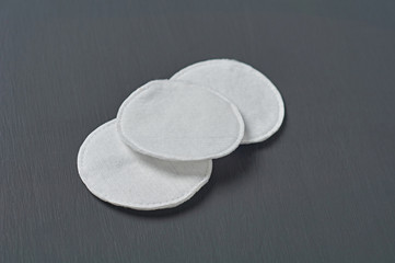 Three round cotton pads for hygiene lies on dark concrete table. Close-up