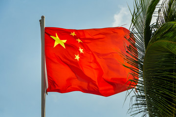One rectangular red colored flag with yellow stars is on a blue sky background