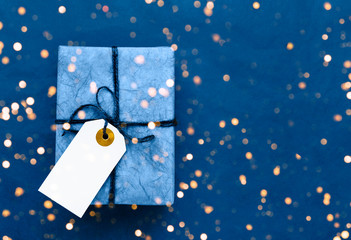 Blue gift box wih gift tag on blue background. Top view. Holiday background. Copy space for text....