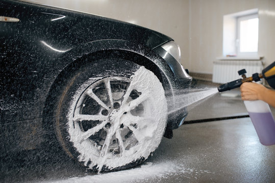 Female washer applies foam to the wheel, car wash