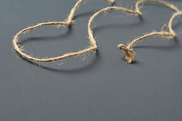 Old curly brown rope lies on dark concrete desk in workshop. Space for text