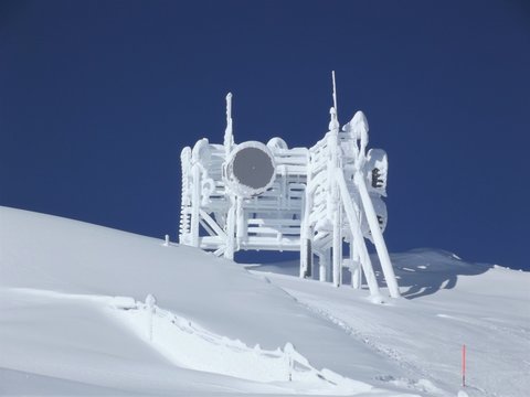 Frozen snow covered communications tower on the top of a mountain