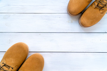 two pairs of yellow winter boots on an old white wooden floor with a copy space on the center