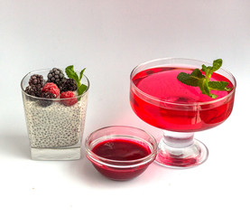 Healthy dessert pudding with chia seeds, frozen summer berries smoothie and jelly in glass cups on a white background.  Decorated with mint, blackberry and raspberry. Diet food and weight loss concept