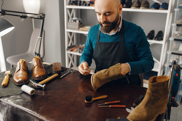Shoemaker stitches the shoe, footwear repair