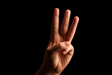 Hand Showing Sign of W Alphabet in American Sign Language (ASL), isolated on black background. Sign language