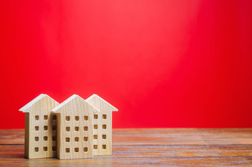 Miniature wooden houses on a red background. Real estate concept. City. Agglomeration and...