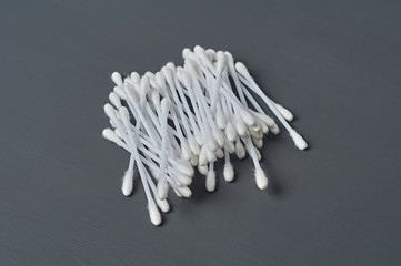 Heap of new cotton sticks for hygiene lies on dark concrete desk. Close-up