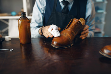 Shoemaker wipes black shoe polish, footwear repair - obrazy, fototapety, plakaty