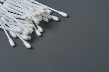 Heap of new cotton sticks for hygiene lies on dark concrete desk. Space for text