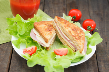 Club sandwiches on plate on wooden table. Salami, lettuce and cheese club sandwich on toasted bread.