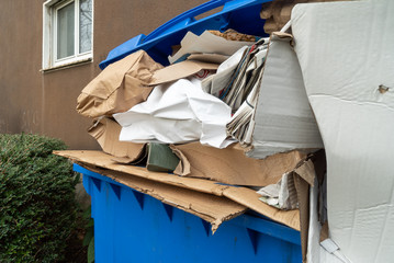 Überfüllter blauer Altpapiercontainer