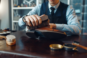 Shoemaker wipes black shoe polish, footwear repair