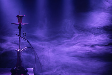 The classic hookah. Beautiful background, with colored rays of light and smoke. The concept of...
