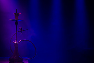 The classic hookah. Beautiful background, with colored rays of light and smoke. The concept of...