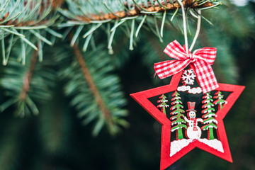green Christmas tree branch with a wooden toy in the shape of a red star, New Year background with copy space for text.