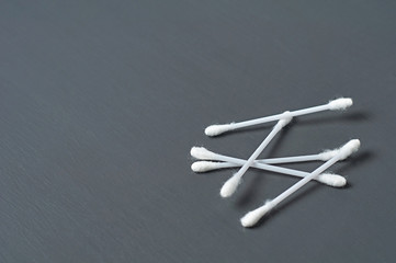 Scattered new cotton sticks for hygiene lies on dark concrete desk. Space for text